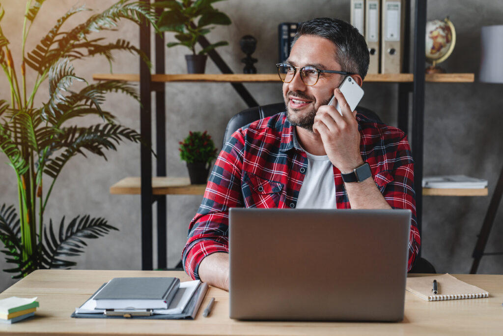 Smiling business owner at a laptop talking on the phone