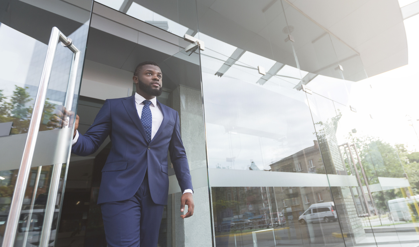 Confident businessman in a suit walking out of an office building